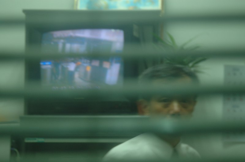 夜盲症與光 王啟瑞<br>地點：台南火車站<br/>準備打烊的火車站，候車大廳的燈光一盞盞的熄滅了，工作人員請我們離開他要關門。<br/>我還是沒拍到想要的相片，走過站長室隨手拍了一張，值班人員大概覺得隱私被侵犯瞪了我一眼，我又補拍這一張就趕快跑走了!<br/>