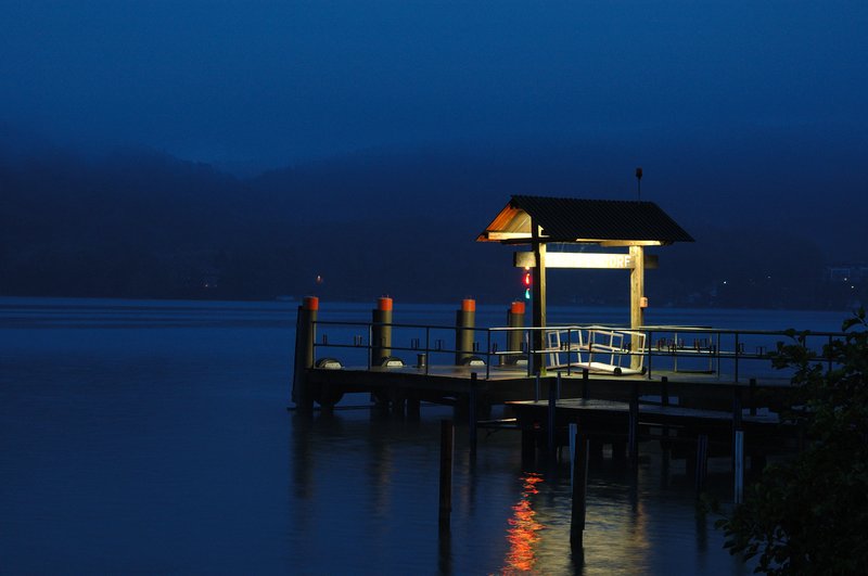 Worthersee湖區<br>我架起腳架，清晨的湖面十分寧靜，覺得湖邊如果加上個人物畫面會更棒，但一大清早大家都在睡覺哪來的人物襯景。於是就決定自己來，腳架離景點約60公尺，相機自拍器最長時間只有20秒，狂奔了幾次都來不及跑到適當的位置。最後只好放棄，留下這張沒有人物的美麗影像。<br/>