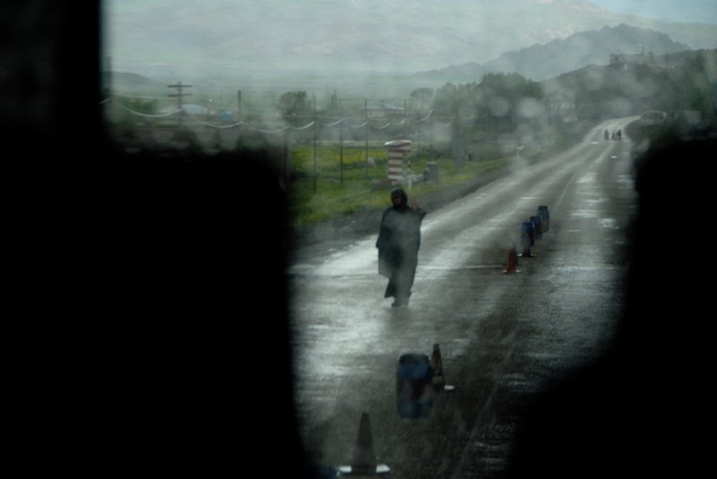 Karabulak<br>下著雨的路上有著士兵巡邏，檢查來往的車輛。我躲在車上座椅後面，偷偷拍下這張相片。沒有想到構圖，沒有想到測光，只求有拍到相片。拍完後我看了一眼，天啊！我知道我拍到好照片。<br/>