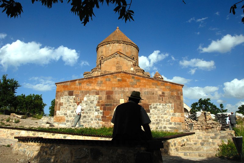 Akdamar Island 阿克達瑪島<br>一位好心的阿伯坐在樹蔭下乘涼，背景是亞美尼亞聖十字教堂。<br/>